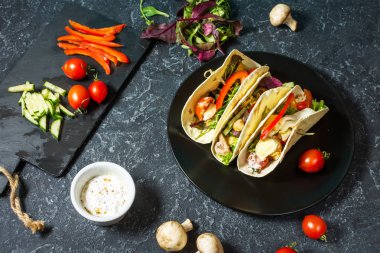 Taze lezzetli Meksika tacos ve gıda maddeleri taş koyu arka plan üzerinde