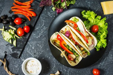 Taze lezzetli Meksika tacos ve gıda maddeleri taş koyu arka plan üzerinde