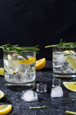 Alkollü içki cin tonik kokteyl limon, biberiye ve taş masada buz ile