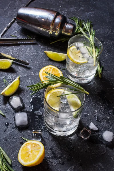 Bevanda alcolica gin tonic cocktail con limone, rosmarino e ghiaccio sul tavolo di pietra — Foto Stock