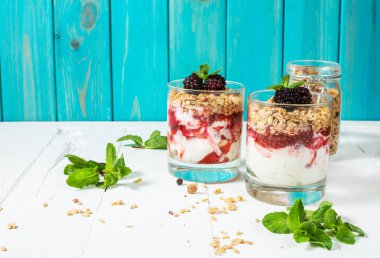 Yoğurt, granola, reçel, cam ahşap arka plan üzerinde blackberry ile sağlıklı katmanlı tatlı