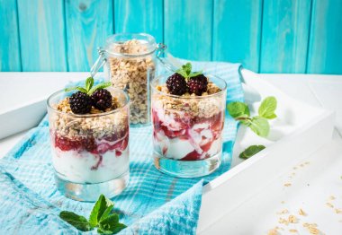 Yoğurt, granola, reçel, cam ahşap arka plan üzerinde blackberry ile sağlıklı katmanlı tatlı