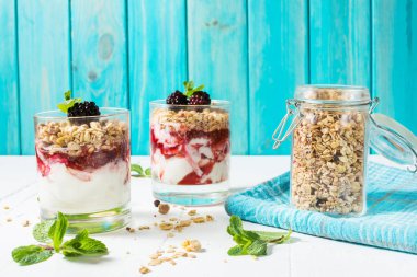 Yoğurt, granola, reçel, cam ahşap arka plan üzerinde blackberry ile sağlıklı katmanlı tatlı