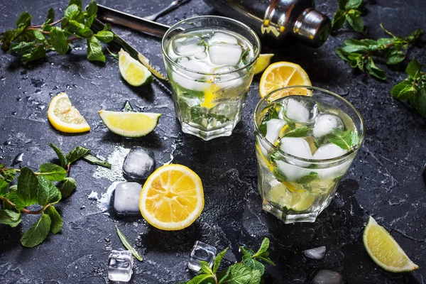 Due bicchieri di cocktail di mojito con lime fresco e menta su una tavola di pietra nera — Foto Stock