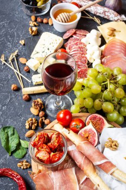 İtalyan antipasto, jambon, peynir, zeytin ve arkaplanda Grissini ekmeği..