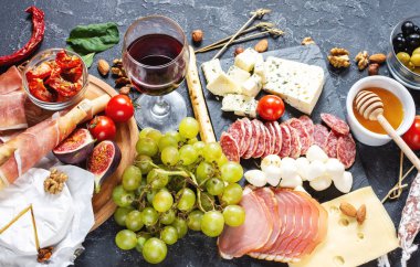 İtalyan antipasto, jambon, peynir, zeytin ve arkaplanda Grissini ekmeği..