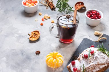 Kış için sıcak şarap ve arkaplanda lezzetli bir Noel pastası.