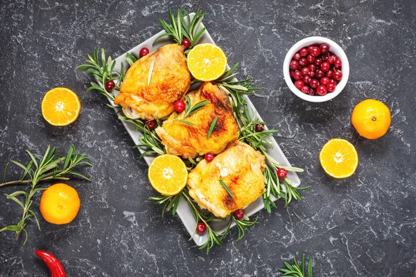 Weihnachtsessen. Hühnerfleisch gebacken mit Preiselbeeren, Mandarinen und Rosmarin auf schwarzem Stein Hintergrund — Stockfoto