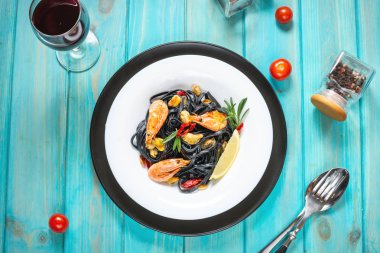 Siyah spagetti. Mavi ahşap arka planda midyeli ve karidesli deniz ürünleri makarnası. Akdeniz Lezzetli Yemekleri.