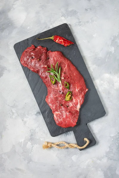 Rauw vers gemarmerd vlees Steak en kruiden op betonnen ondergrond — Stockfoto
