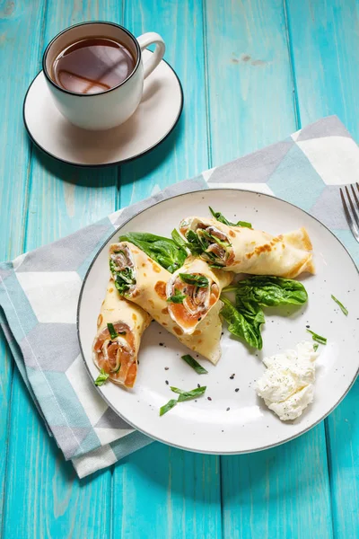 Delicioso desayuno o brunch - crepes con salmón ahumado, espinacas y crema agria sobre fondo de madera . — Foto de Stock