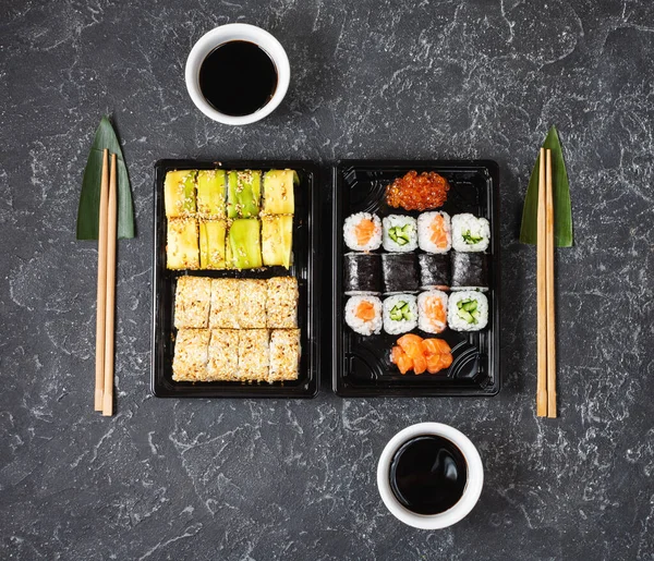 Různé druhy sushi podávané na černém kamenném pozadí. — Stock fotografie