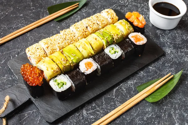Různé druhy sushi podávané na černém kamenném pozadí — Stock fotografie