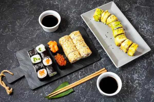 Různé druhy sushi podávané na černém kamenném pozadí — Stock fotografie
