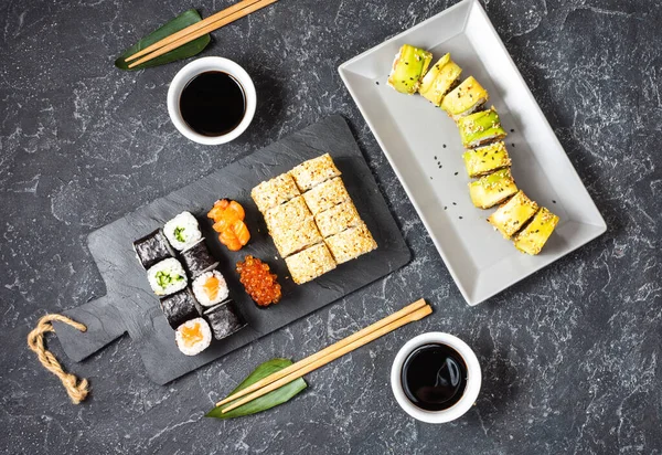 Různé druhy sushi podávané na černém kamenném pozadí. — Stock fotografie