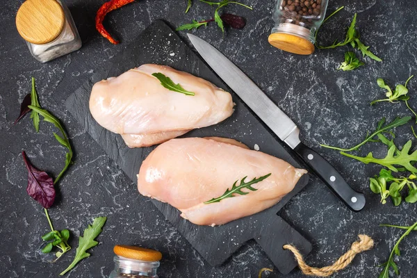 Fresh raw chicken fillet, spices and herbs on black stone background — Stock Photo, Image