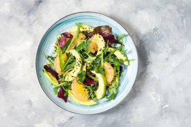 Beton zeminde vejetaryen greyfurt, avokado ve roka salatası. Üst görünüm