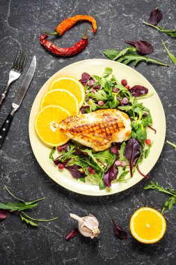 Izgara tavuk göğsü ve koyu taştan arka planda yeşil salata. Sağlıklı beslenme konsepti. Üst görünüm