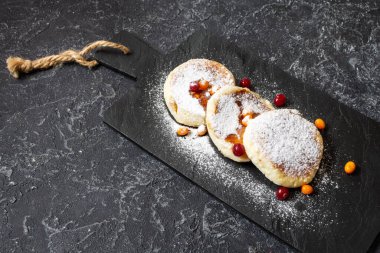 Koyu taşlı arka planda süzme peynirli krep. Ekşi kremalı Syrniki. Ev yapımı yemek..