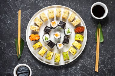 Siyah taştan bir arka planda servis edilen çeşitli suşiler. Üst görünüm