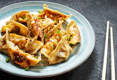 Japon gyoza 'sı ya da siyah taş arka planda soya soslu hamur tatlısı.