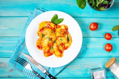 Domates soslu Ravioli ve ahşap kaplamalı fesleğen. Lezzetli makarna. Üst görünüm