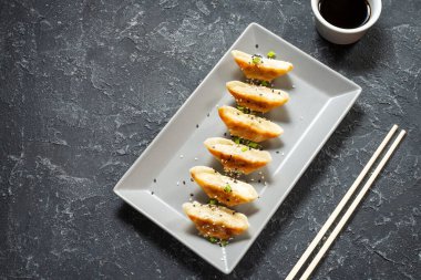Japon gyoza 'sı ya da siyah taşlı arka planda soya soslu hamur tatlısı. Üst görünüm