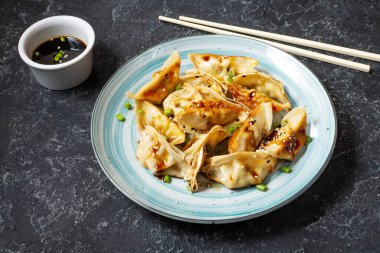 Japon gyoza 'sı ya da siyah taş arka planda soya soslu hamur tatlısı.