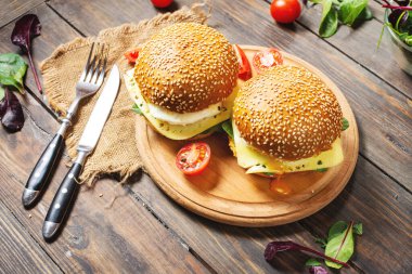 İki hamburger, tavuk, sade ahşap arka planda kızarmış yumurta ve peynir.