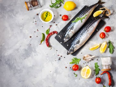 Beton zemin üzerinde limonlu ve baharatlı taze çiğ uskumru. Üst görünüm ve kopyalama alanı