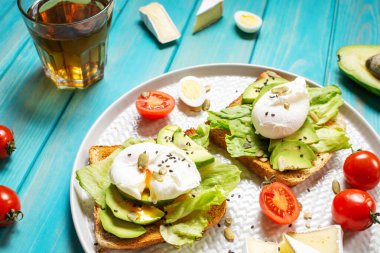 Sağlıklı sandviç - haşlanmış yumurta ve kızarmış ekmek üzerine domatesli mavi ahşap arka plan..