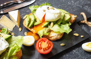Sağlıklı sandviç - haşlanmış yumurta ve kızarmış ekmek üzerine domatesli siyah taş zemin..