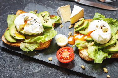 Sağlıklı sandviç - haşlanmış yumurta ve kızarmış ekmek üzerine domatesli siyah taş zemin..