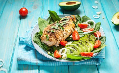 Izgara tavuk göğsü ve ıspanaklı avokado salatası ve ahşap kaplamalı kiraz domatesleri. Sağlıklı yemek, ketojenik diyet, öğle yemeği konsepti..