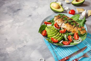 Izgara tavuk göğsü ve ıspanaklı avokado salatası ve çimento kaplı kiraz domatesleri. Sağlıklı yiyecekler, ketojenik diyet, öğle yemeği konsepti. Boşluğu kopyala