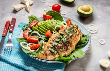 Izgara tavuk göğsü ve ıspanaklı avokado salatası ve çimento kaplı kiraz domatesleri. Sağlıklı yemek, ketojenik diyet, öğle yemeği konsepti..