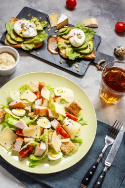 Kavrulmuş yumurtalı taze Sezar salatası ve beton zemin üzerinde avokado. Sağlıklı ve diyet gıda konsepti.