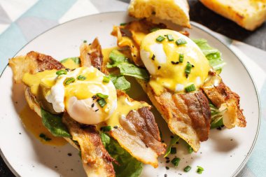 Benedict yumurtalı sandviç, pastırma ve siyah taşlı salata..