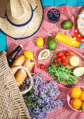 Taze meyve, sebze, salata, portakal suyu, çiçekler ve kırmızı ekose ekmekli ekmek ile ev yapımı piknik. Güzel natürmort. Üst görünüm