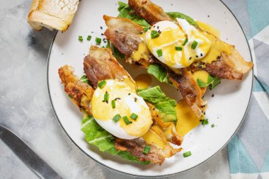 Benedict yumurtalı sandviç, arka planda pastırma ve salata. Üst görünüm.