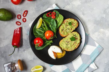 Avokado Meksika soslu avokado soslu sağlıklı tost haşlanmış yumurta, kiraz domatesleri ve beton arka planda salata. Üst Manzara. Kahvaltı.