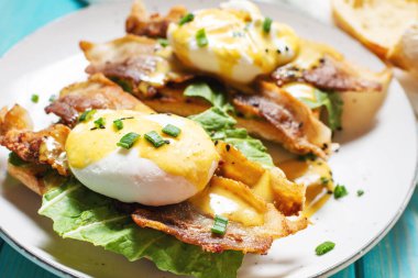 Benedict yumurtalı sandviç, domuz pastırması ve ahşap kaplama salata..