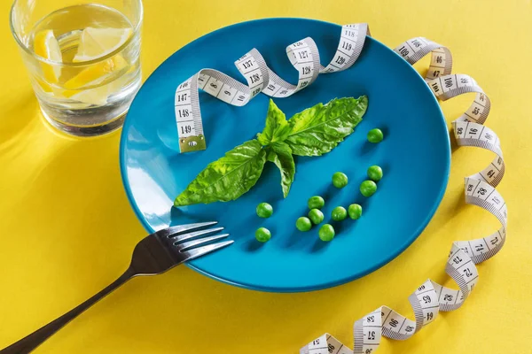 Diet blue plate with centimeter, peas and basil