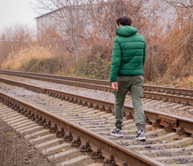 Demiryolunda yürüyen bir adam. Arkadan bak.