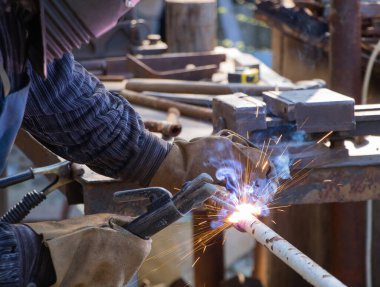 Fabrikadaki metal boruları kaynak yapan işçi.