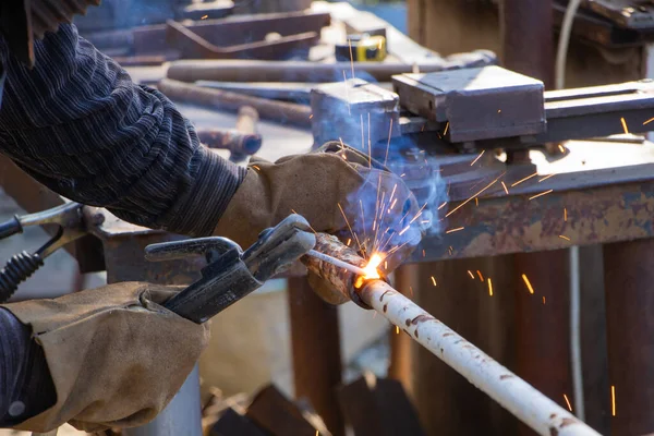 The worker welding metal pipe at the factory