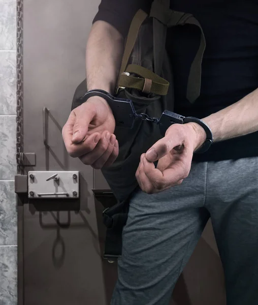 Bir suçlunun elleri ile hapishane hücresinin arka planına kelepçelenmiş. Bir hırsızı tutuklamak. Gözaltı