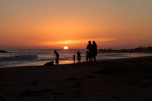 Silhouette de personnes profitant de la plage au coucher du soleil — Photo