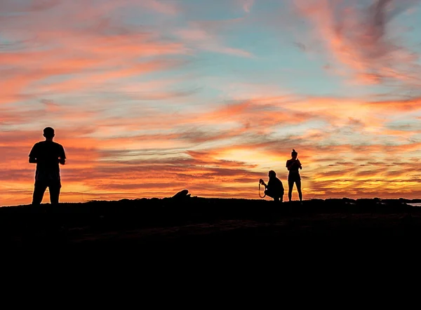 Silhouette di persone che si godono la spiaggia al tramonto — Foto Stock