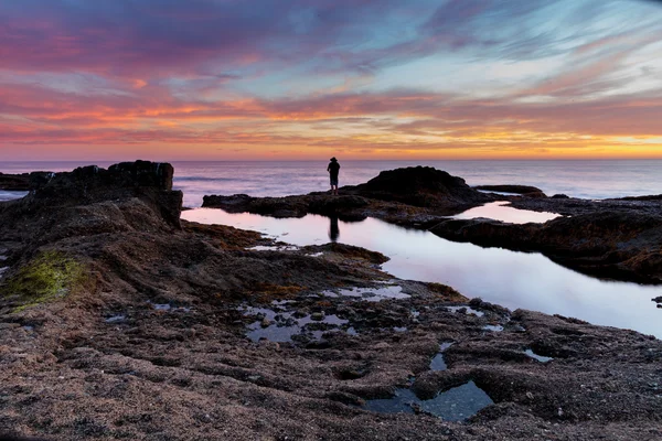 Lone man on the rocks at sunset — Stock Photo, Image